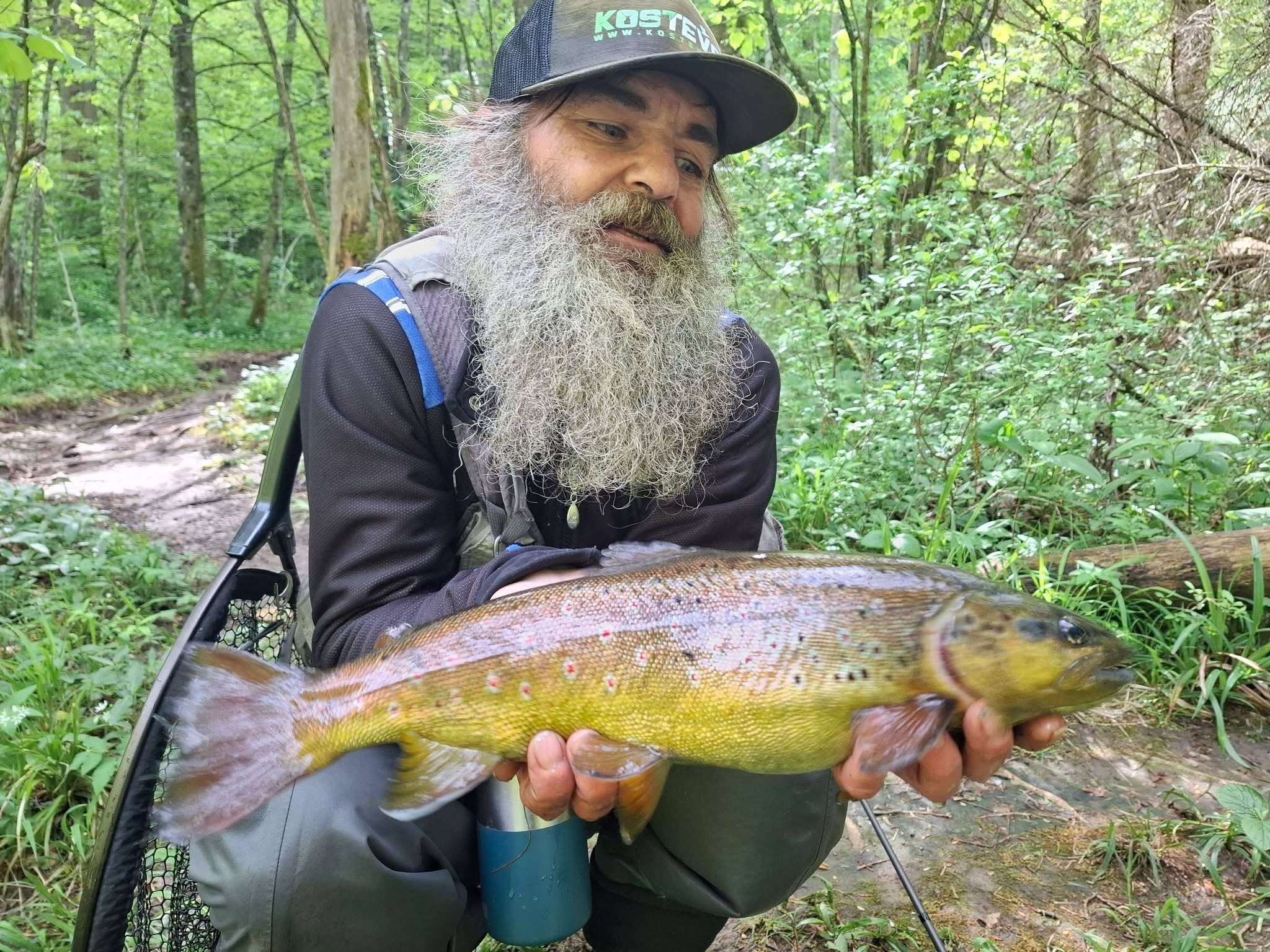 Član društva s velikom pastrvom u šumi