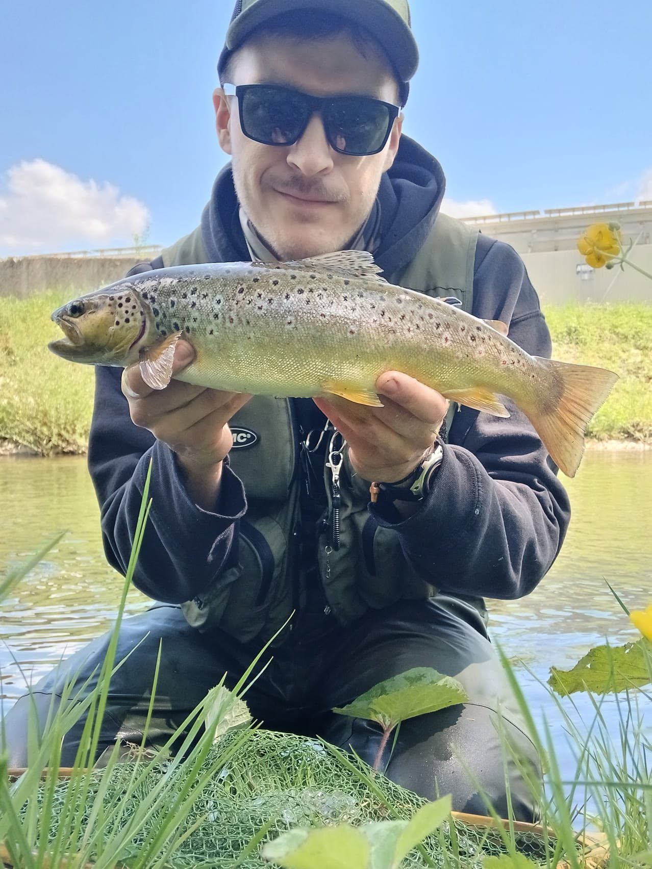 Mladi ribič s ulovljenom pastrvom